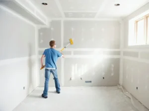 a man sanding drywall a room