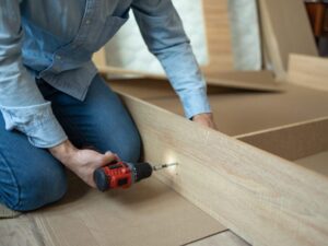 Person assembling furniture with a drill, demonstrating general handyman services offered by BrightWise Handyman Services.